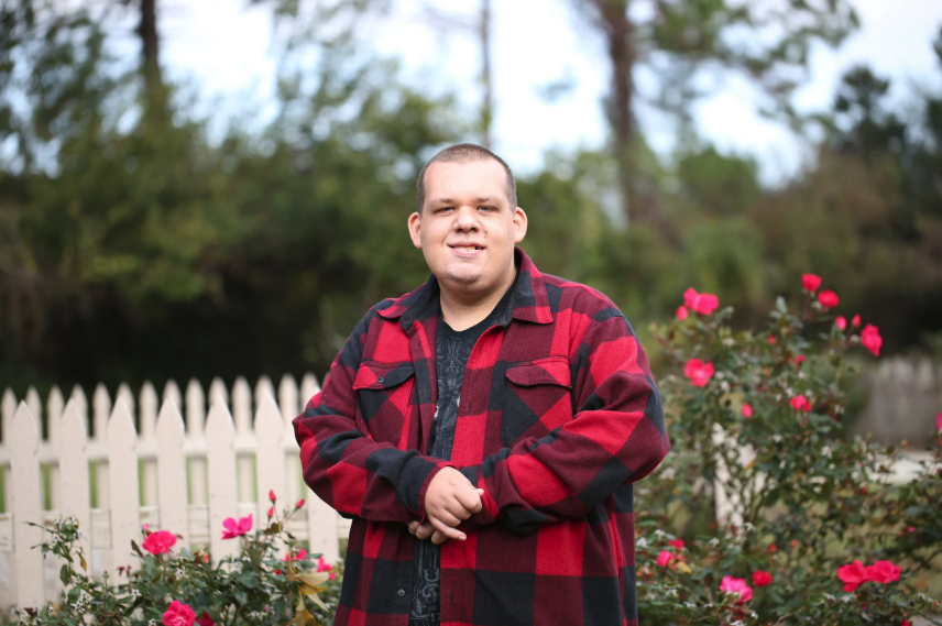 Un jeune homme ayant une DI dans un jardin de rose