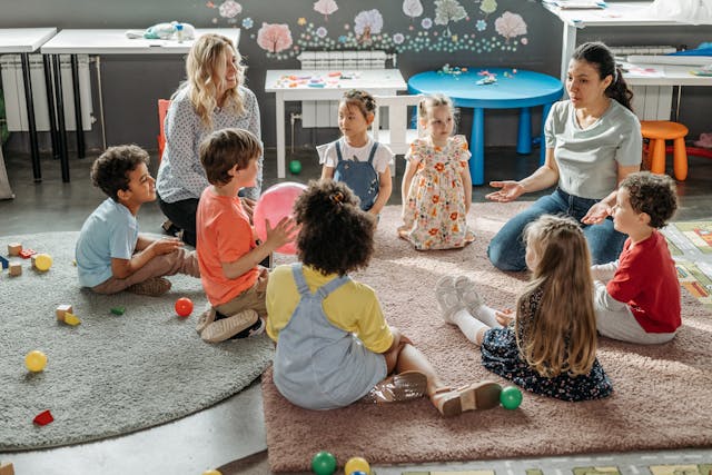 Inclusion dans les services de garde : des enfants assis en cercle dans avec leurs deux éducatrices dans une garderie
