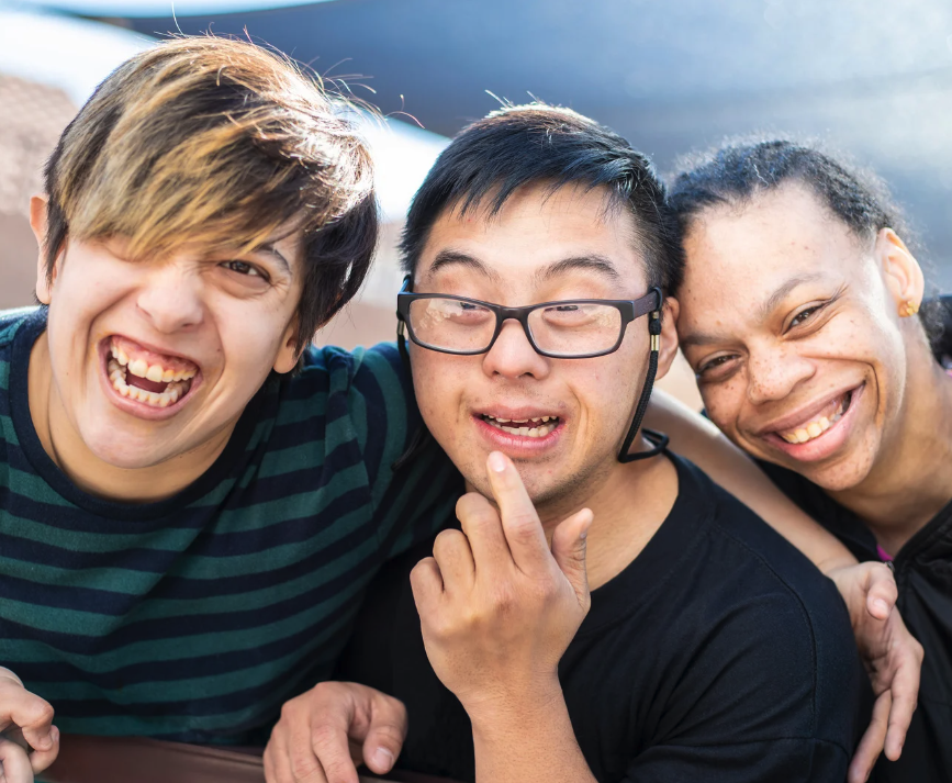 Trois jeunes adultes ayant une déficience intellectuelle sourient