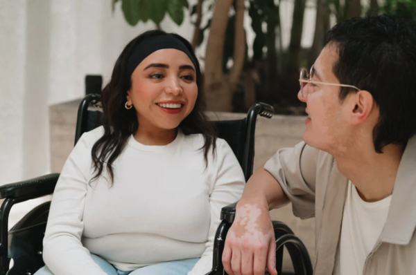 jeune femme dans son fauteuil roulant discute avec un ami