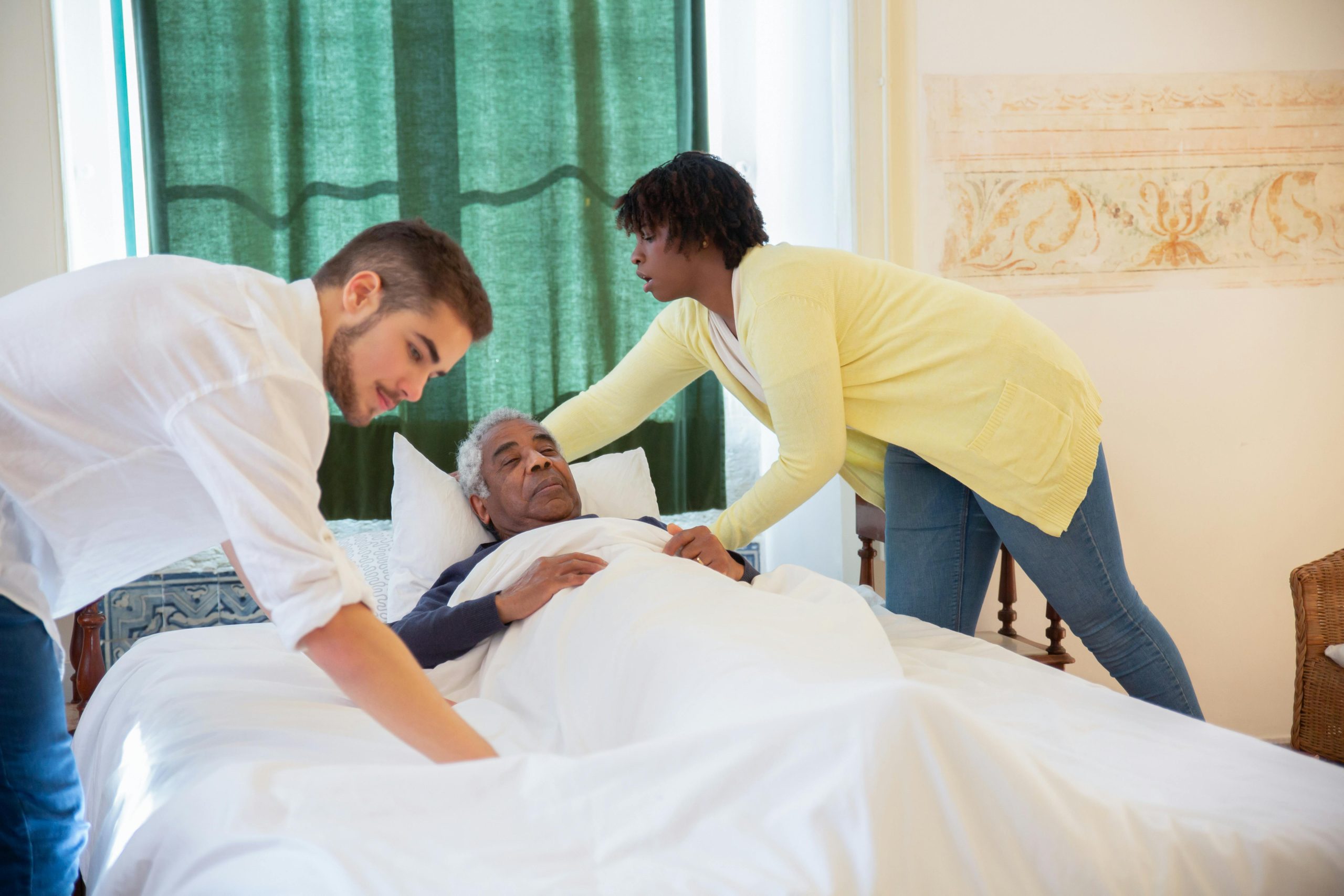 soins palliatifs : 2 préposés aux bénéficiaires s'occupe du confort d'un patient dans son lit
